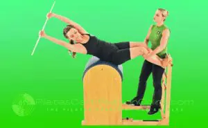 A woman is doing pilates on the barrel