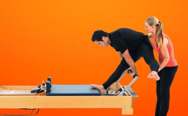 A man and woman are doing pilates on the reformer.