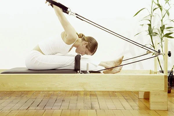 Una mujer en un Reformer de Pilates en The Pilates Studio de Los Ángeles demuestra una auténtica formación online para la certificación de Pilates.