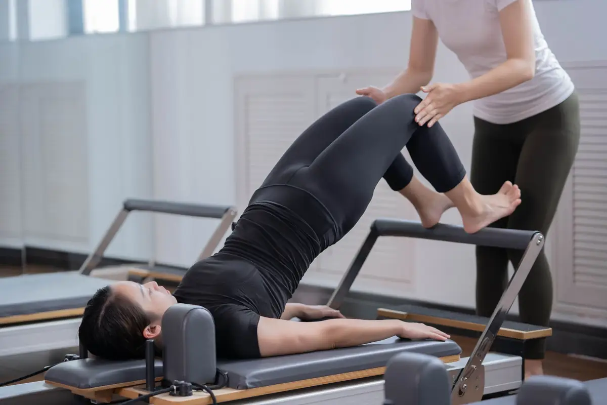 Pilates instructor guiding a student through a Reformer exercise